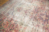 Detailed view of antique Kerman carpet's threadbare regions, exposed knot heads, and faded floral patterns.
