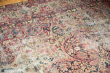 Kerman carpet's nuanced wear showcasing scrolling floral arabesques in cochineal red and navy blue.