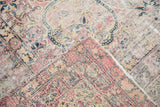 Antique Kerman rug corner reveals worn floral pile, exposed knot heads, and hand-knotted foundation.