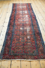 Vintage Lilihan runner with germinating plant motif, dusty rose field, blue border, and textured wear.
