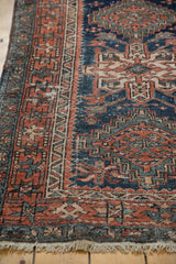 Vintage Karaja rug with geometric terracotta and navy border, visible wear, and intact fringe.