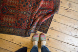 Partially folded rug revealing glossy raspberry red pile with navy and ivory floral vines.