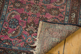 Raspberry red Herati motif, worn pile, tattered fringe, and hand-knotted foundation of Lilihan rug.