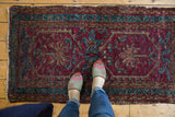 Vintage Lilihan rug showing oversized raspberry red and blue floral motifs with meandering borders.