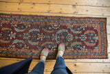 Vintage Heriz runner with Aubergine field, European-influenced Herati motifs, and visible tattered end.