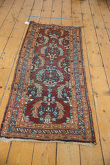 Vintage Heriz runner's end, showing its tattered fringe and distinct patterned border.