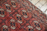 Repeating stylized gul motifs with intricate weave in dusty raspberry, navy, and ivory.