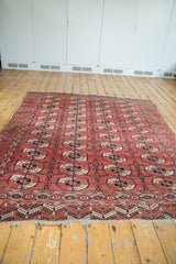 Repeating stylized gul design motif on a vintage Bokhara carpet, dusty raspberry and navy.
