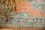 Distressed Oushak carpet's worn dusty tangerine orange pile with blue and teal border patterns.