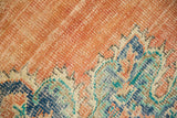 Worn dusty tangerine Oushak rug field with scalloped blue and ivory Rococo motifs.