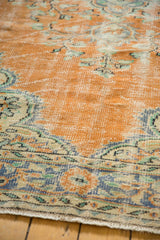 Worn dusty tangerine Oushak carpet pile showing faded blue and ivory patterns.