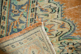 Distressed tangerine and blue pile texture, revealing the vintage rug's hand-knotted reverse.