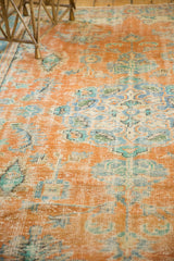 Close-up of distressed Oushak rug pile showing tangerine, blue, and green worn knot heads.