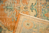 Distressed Oushak rug corner revealing mostly even wear, fringe, and woven reverse.