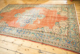 Distressed vintage Oushak carpet corner with worn tangerine field and blue-green Rococo details.