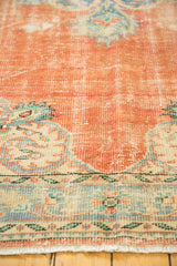 Distressed Oushak carpet border with ivory, blue-green Rococo motifs alongside tangerine pile.