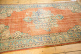 Distressed tangerine orange Oushak border with ivory and dusty blue floral motifs.