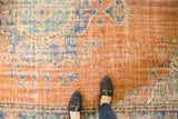 Distressed vintage Oushak rug showcasing a burnt orange field and worn blue Rococo florals.