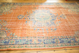 Distressed Oushak carpet with European rococo floral motifs in burnt orange and blue.