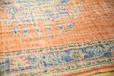 Worn dusty orange field and royal blue border of a vintage Oushak rug with Rococo florals.
