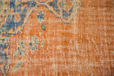 Distressed burnt orange Oushak pile with blue florals, revealing mostly even wear and faint foundation.