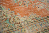 Distressed burnt orange texture with vibrant floral motifs on a vintage Oushak rug.