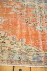 Distressed Oushak rug pile with faded burnt orange, powder blue Rococo floral motifs, and fringe.