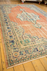 Distressed vintage Oushak rug corner with worn knot heads, teal border, and fringe.