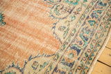 Vintage Oushak rug detail: distressed tangerine field with faint foundation and blue, teal border.