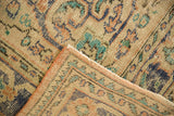 Folded corner of vintage Oushak rug, highlighting distressed pile, secured edge, teal and tangerine motifs.