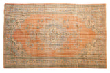 Faded peach orange vintage Oushak carpet with slate blue roundel medallion and rococo floral motifs.