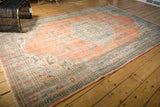 Distressed peach field of vintage Oushak, showing worn texture and European floral border.