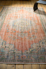 Visible wear on faded peach and blue pile of a vintage distressed Oushak rug.