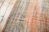 Distressed texture of the vintage Oushak rug, showing faded peach, blue, and mint green colors.