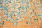 Distressed vintage Oushak rug's faded tangerine, teal, ivory Rococo floral geometric pattern and pile wear.