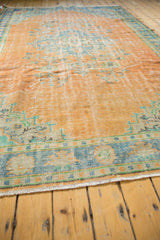 Distressed Oushak rug border showing faded tangerine, royal blue, mint, and knot head wear.