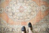 Distressed vintage Oushak carpet detail showing Rococo stylized motifs and faded apricot, charcoal, ivory.
