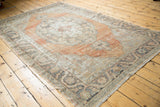 Distressed vintage Oushak rug with faded apricot medallion and meandering charcoal vine border.