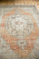 Distressed vintage Oushak rug pile with faded apricot, charcoal, and ivory Rococo motifs.