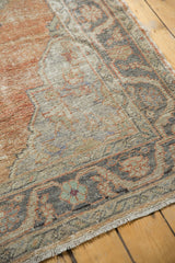 Distressed Oushak carpet border showing faded apricot, charcoal, Rococo stylized motifs, and fringe.
