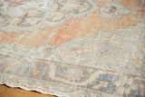 Close-up of the distressed Oushak rug's worn texture, showcasing apricot and charcoal tones.