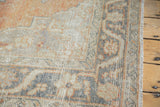 Distressed Oushak rug corner, faded apricot, charcoal, beige meandering vine border.