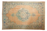 Vintage distressed Oushak rug with aqua blue Rococo medallion on a soft beige field.