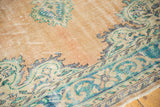 Distressed Oushak rug's dusty rose field and aqua meandering vine border, with visible wear.