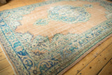 Distressed vintage Oushak rug corner detailing blue, aqua meandering vine main border.