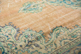 Distressed vintage Oushak rug, showing worn sandy beige pile with aqua blue scalloped vine border.