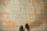 Distressed vintage Oushak carpet showing faded tangerine, royal blue, and mint green floral motifs.