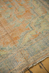 Distressed vintage Oushak carpet pile showing faded orange, blue, ivory tones and fine fringe detail.
