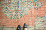 Distressed vintage Oushak rug with faded terracotta field and intricate floral patterns.