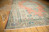 Distressed Oushak rug's main border with meandering vine, showing soft terracotta and mint hues.